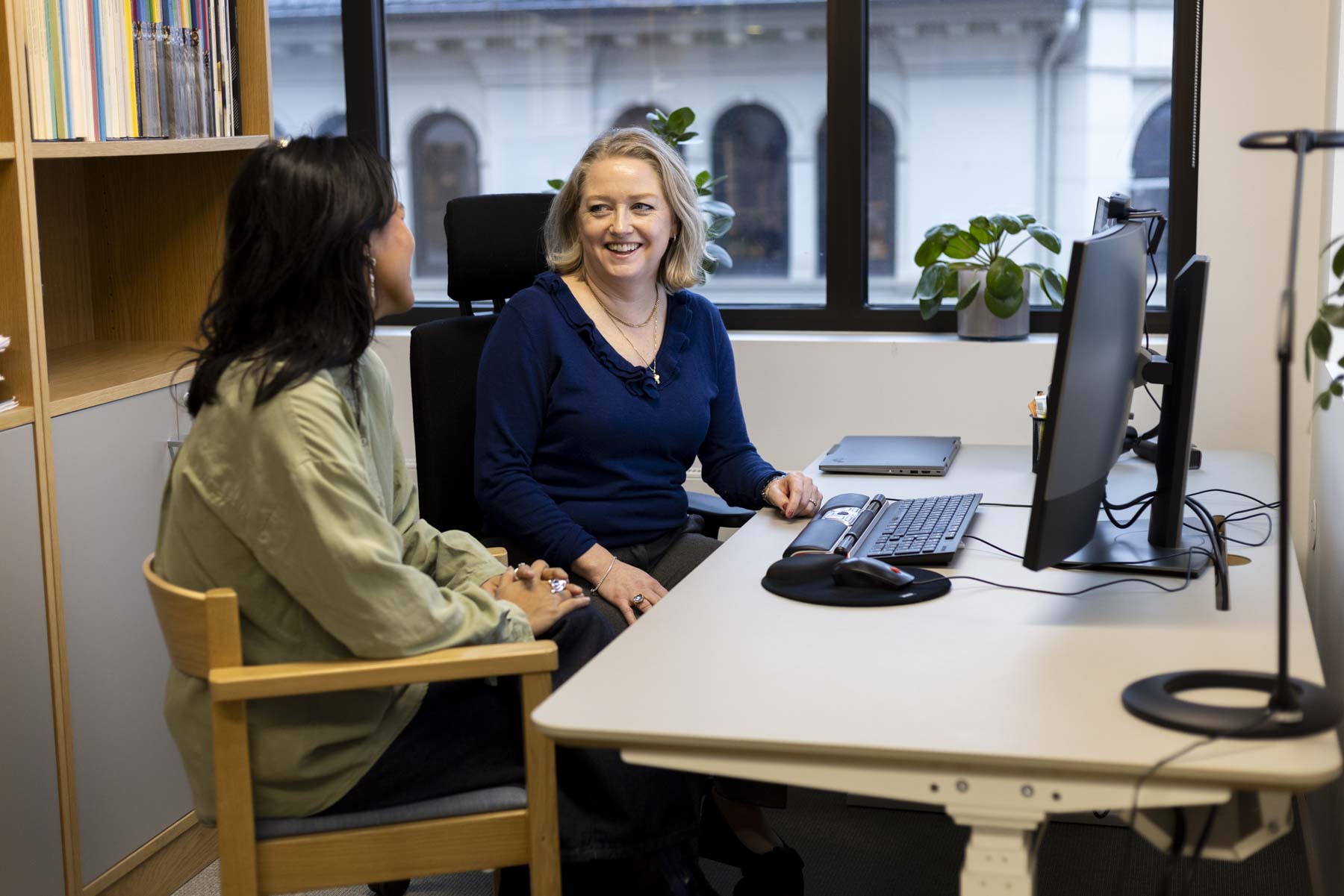 To kvinner sitter på kontor foran pc.