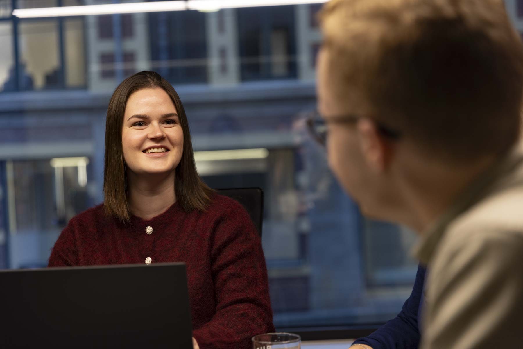 Intervjusituasjon. Dame foran pc ser på mann som har ryggen til kamera.