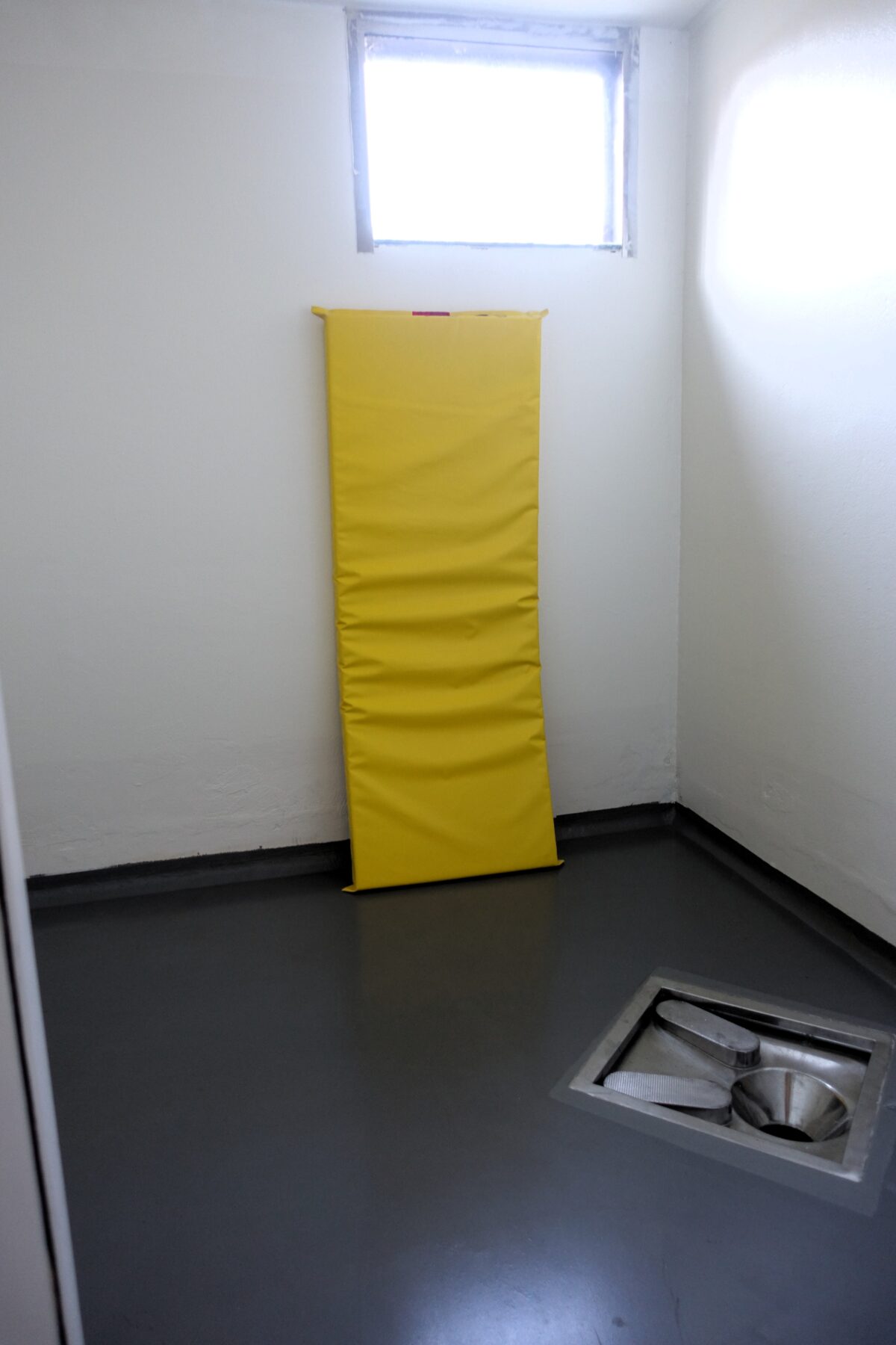 Sikkerhetscelle med gul madrass opp mot veggen.