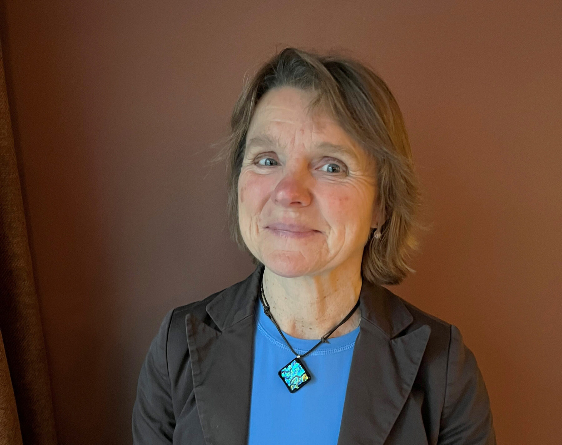 Portrettfoto dame med kort hår, blå topp og mørk blazer